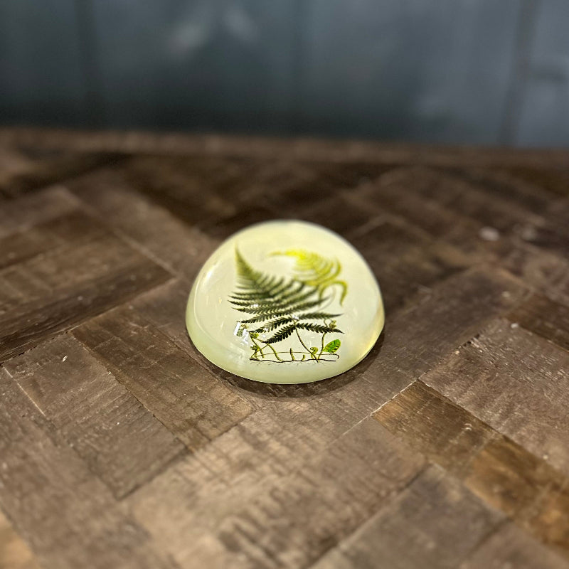 Round ceramic stone with a leaf design on a textured surface