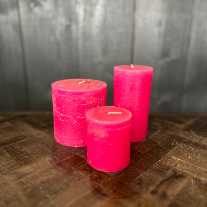 Three pink candles on a wooden surface with a gray background