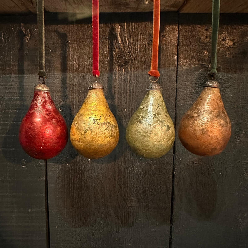 A set of round pear-shaped decorations in various colors including red, gold, green, copper, and silver, each with a velvet ribbon for hanging.