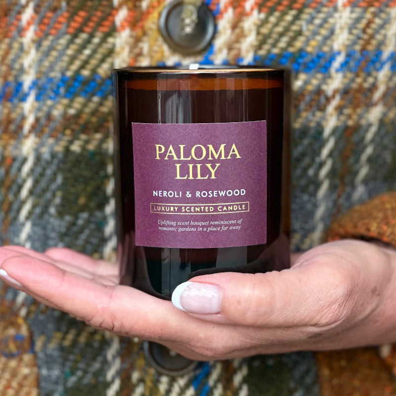 Hand holding a scented candle labeled &