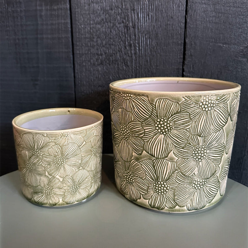 Two ceramic planters with floral patterns on a dark wooden background
