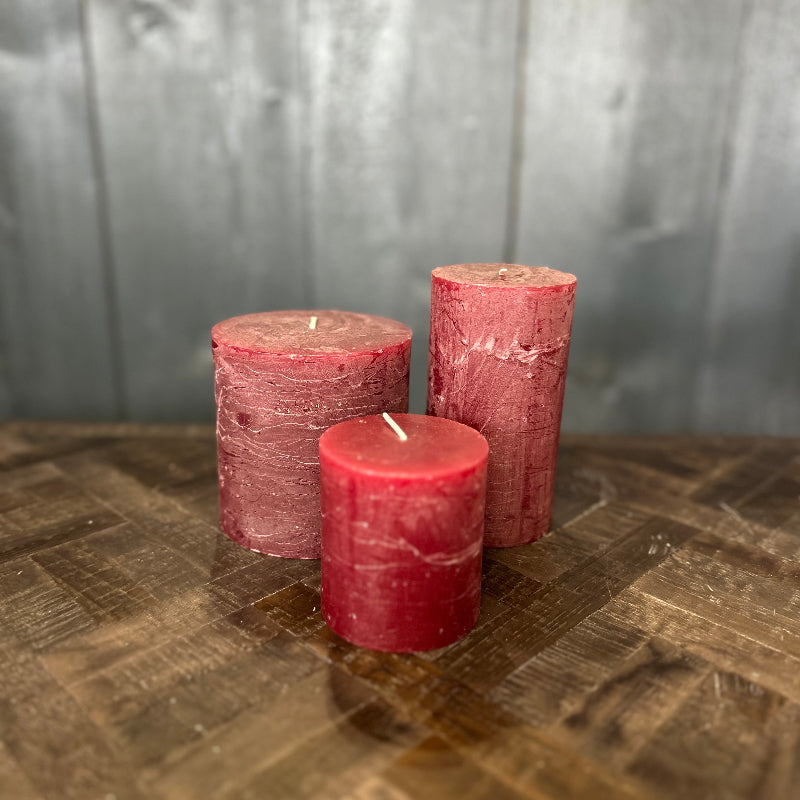 Three red candles on a wooden surface with a gray background
