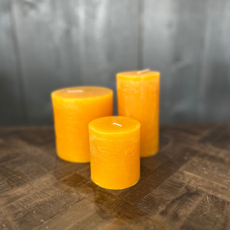 Three yellow candles on a wooden surface with a dark background