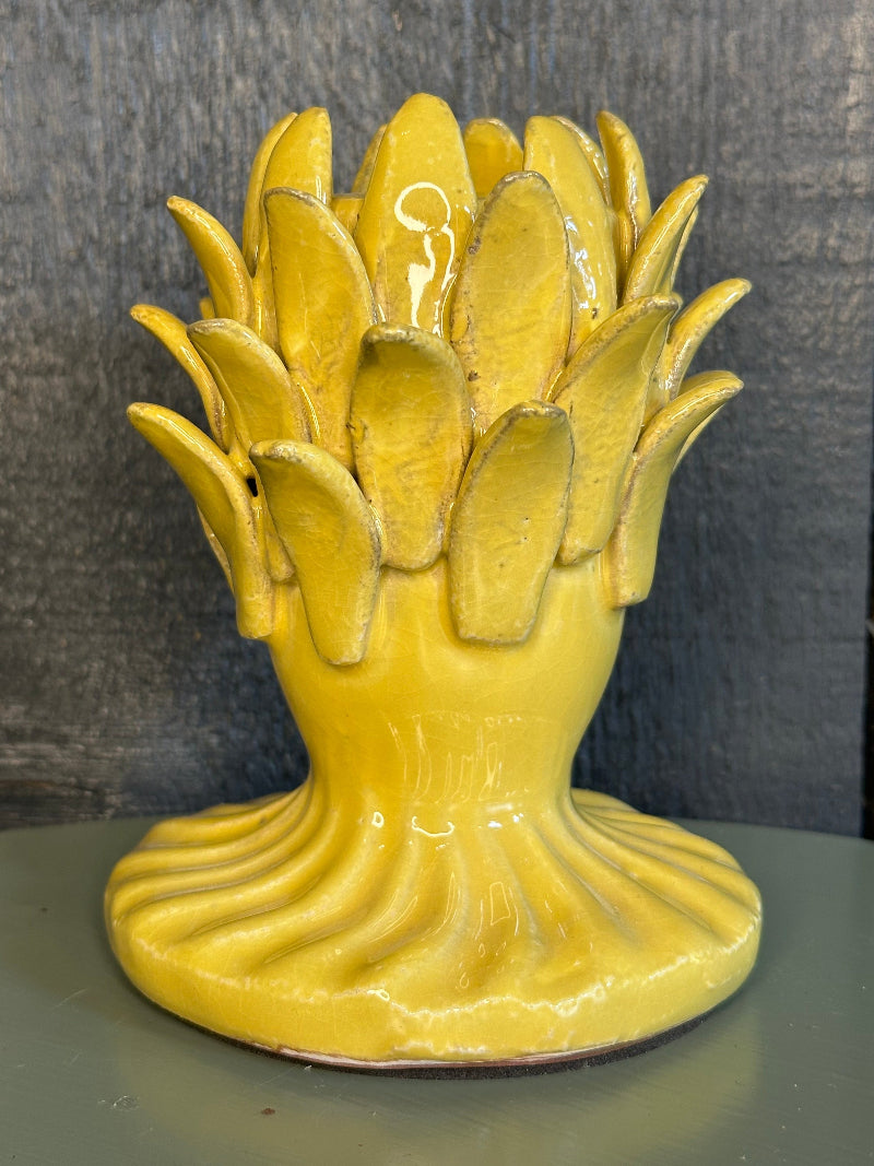 Yellow ceramic candle holder with a unique design on a gray surface