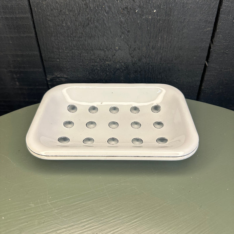 White soap dish with holes attached to a black surface