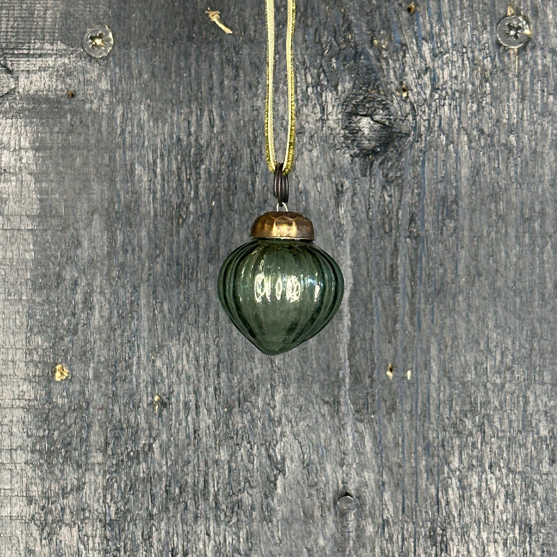 Green glass ornament with gold top on a textured gray background