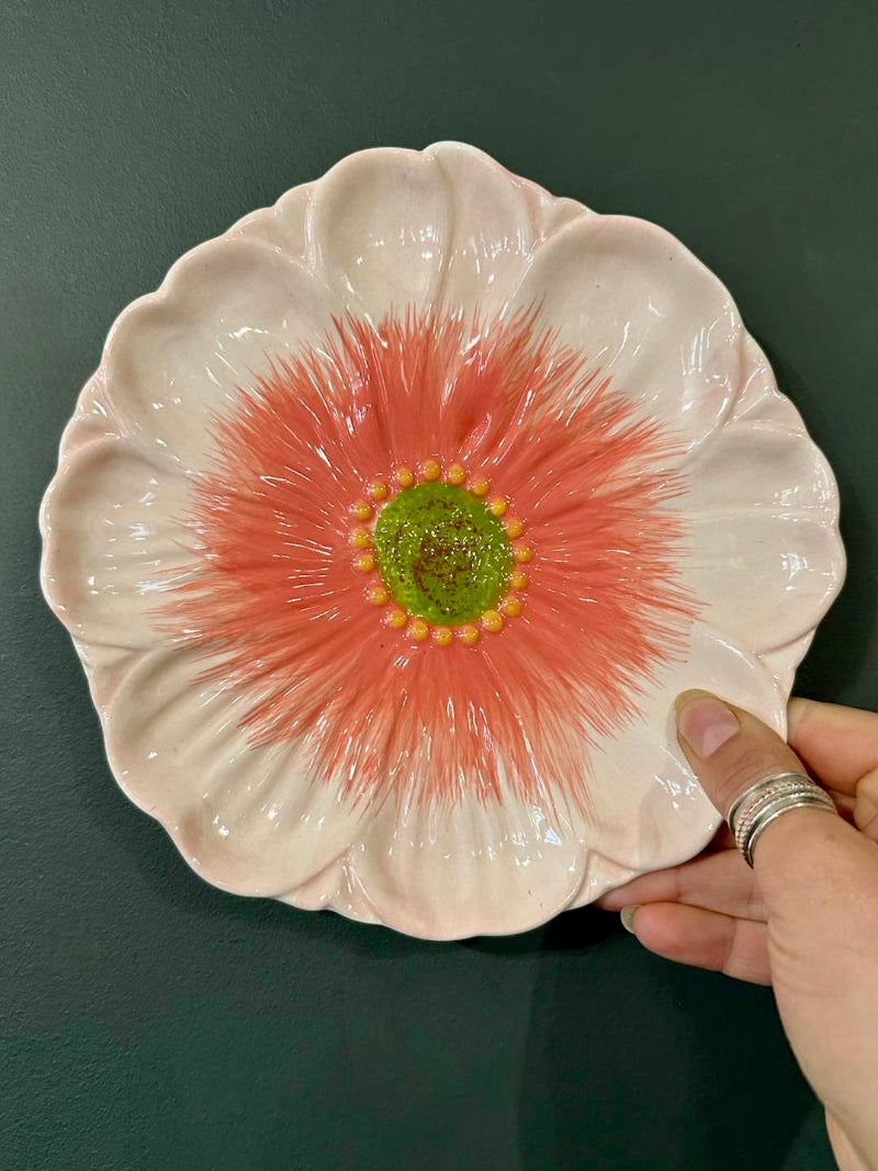 Ceramic plate with floral design held by a hand against a dark background