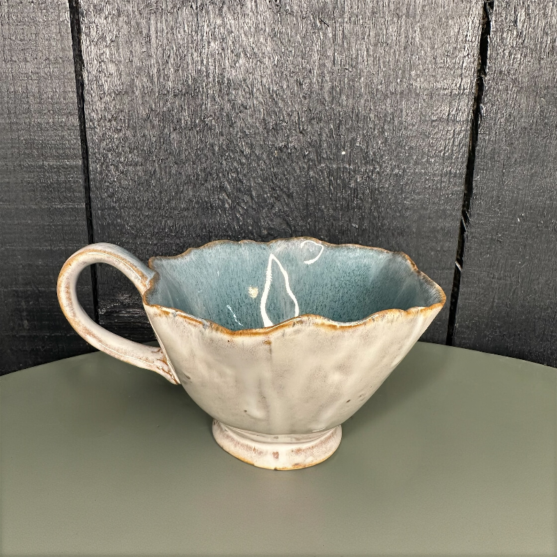 Ceramic cup with a textured handle and base on a dark surface