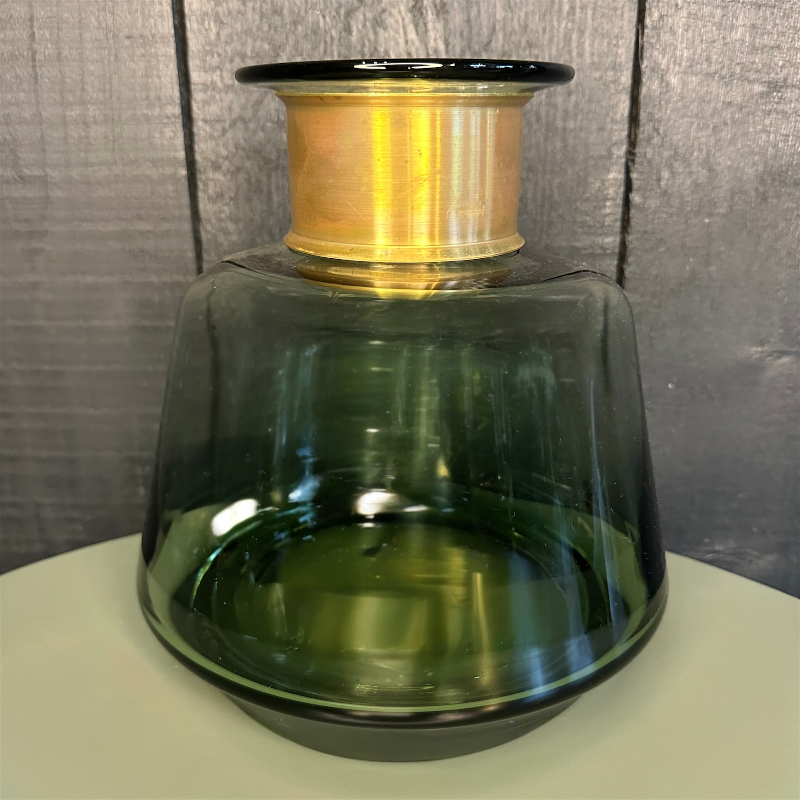 Decorative vase with green base and gold spool on top against a gray background