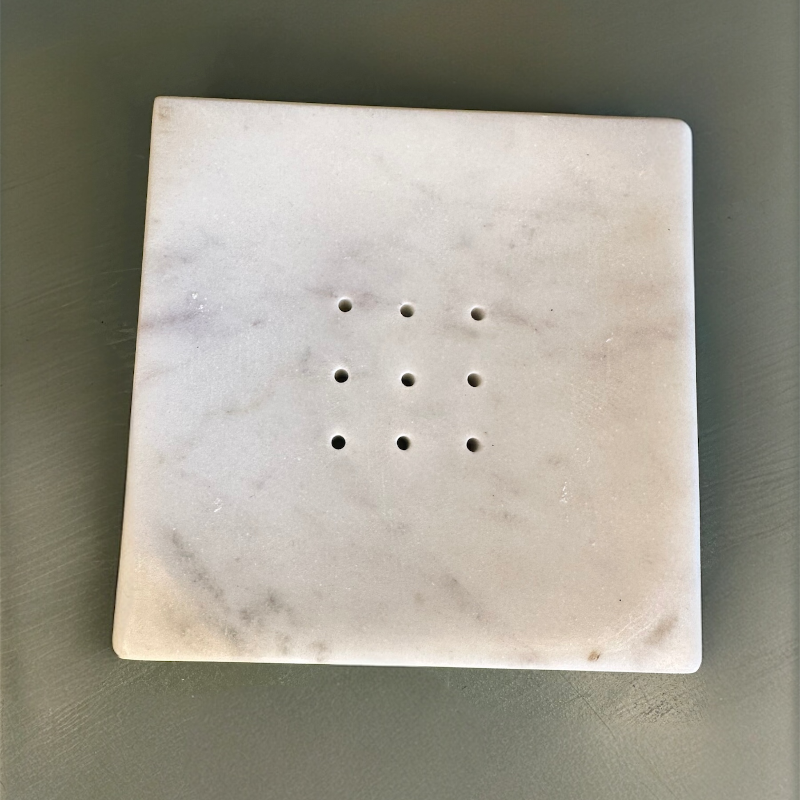Square marble stone with holes on a gray background