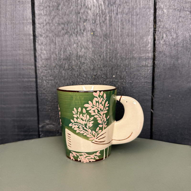 Green mug with floral design on a gray surface and wooden background