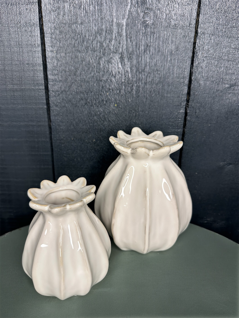 Two white ceramic vases on a dark surface with a dark background