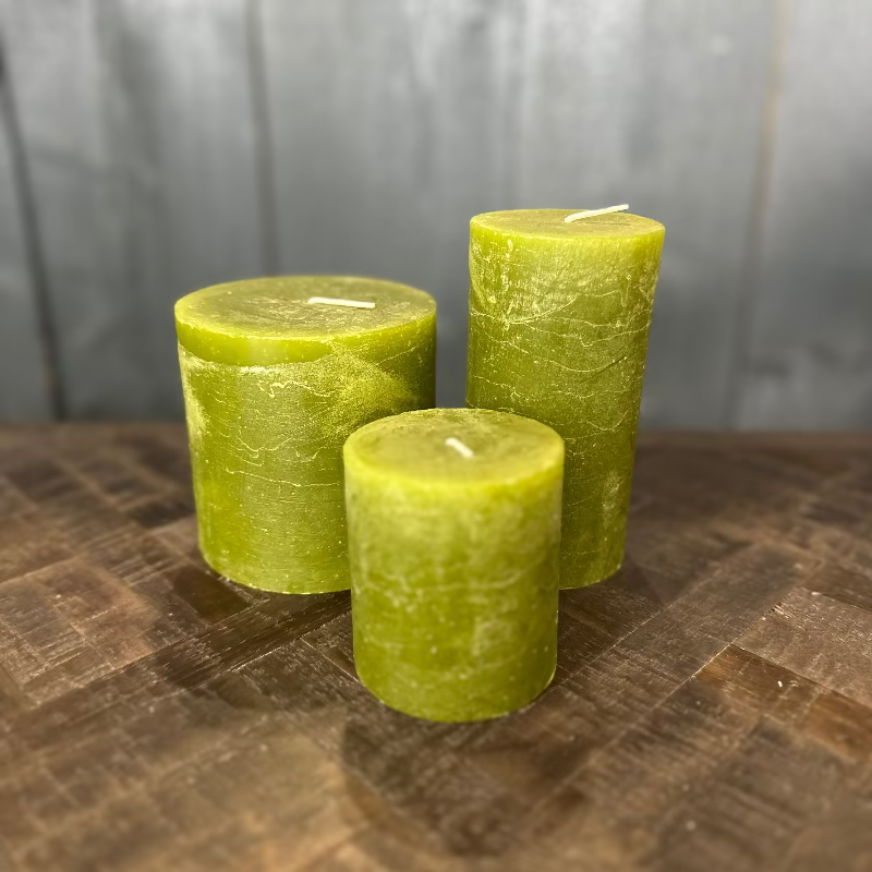 Three green candles on a wooden surface with a gray background