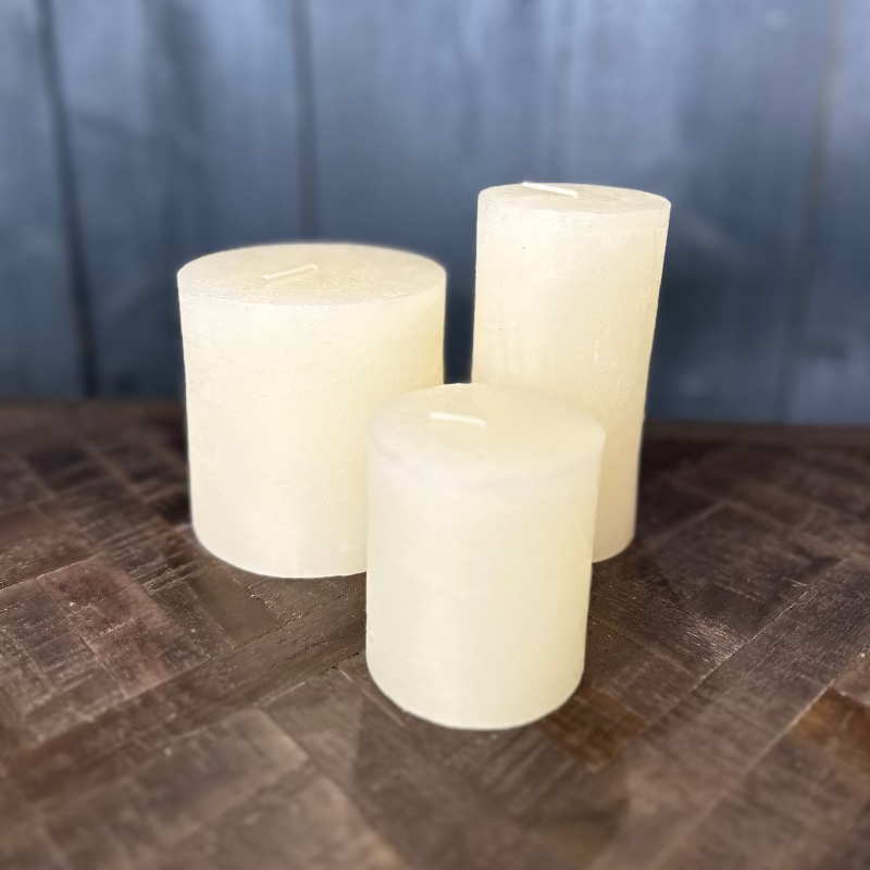 Three white candles of different sizes on a textured surface with a gray background