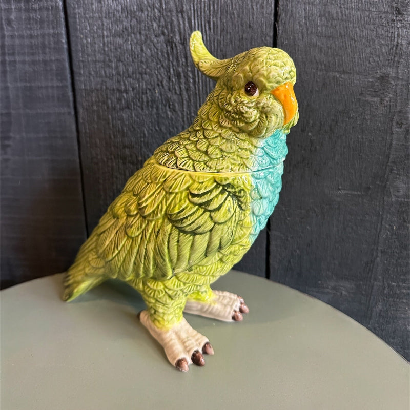 Decorative parrot figurine on a gray surface with a dark wooden background