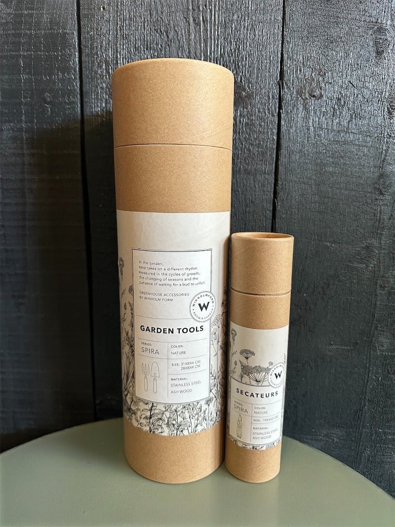 Two cardboard garden tool packaging tubes with labels on a wooden surface.