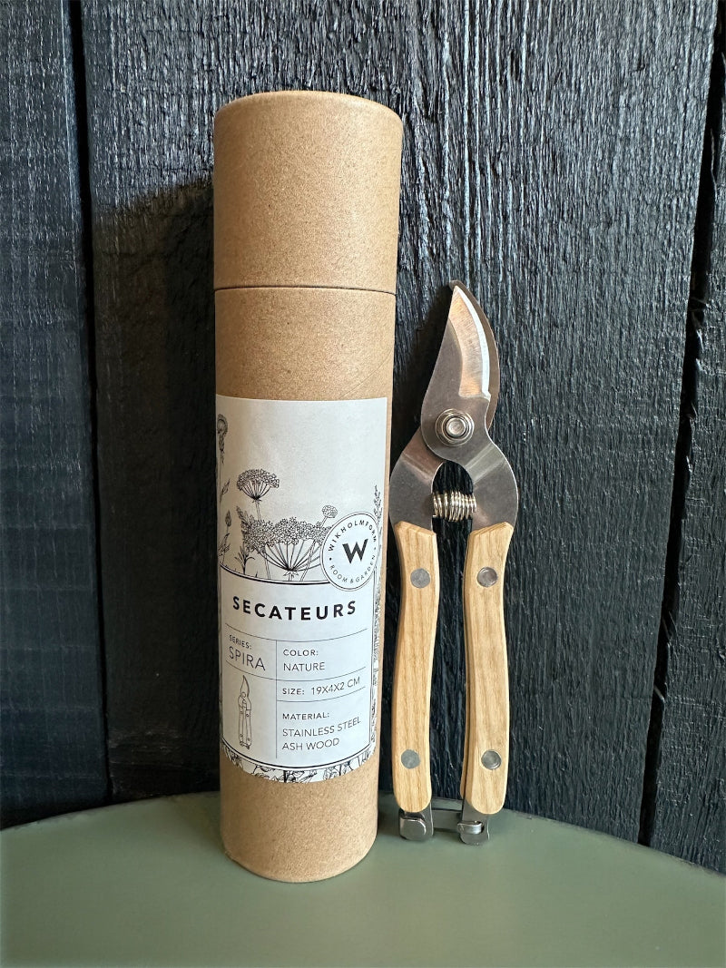 A pair of secateurs with stainless steel blades and ash wood handles, next to a cylindrical cardboard packaging with branding information.