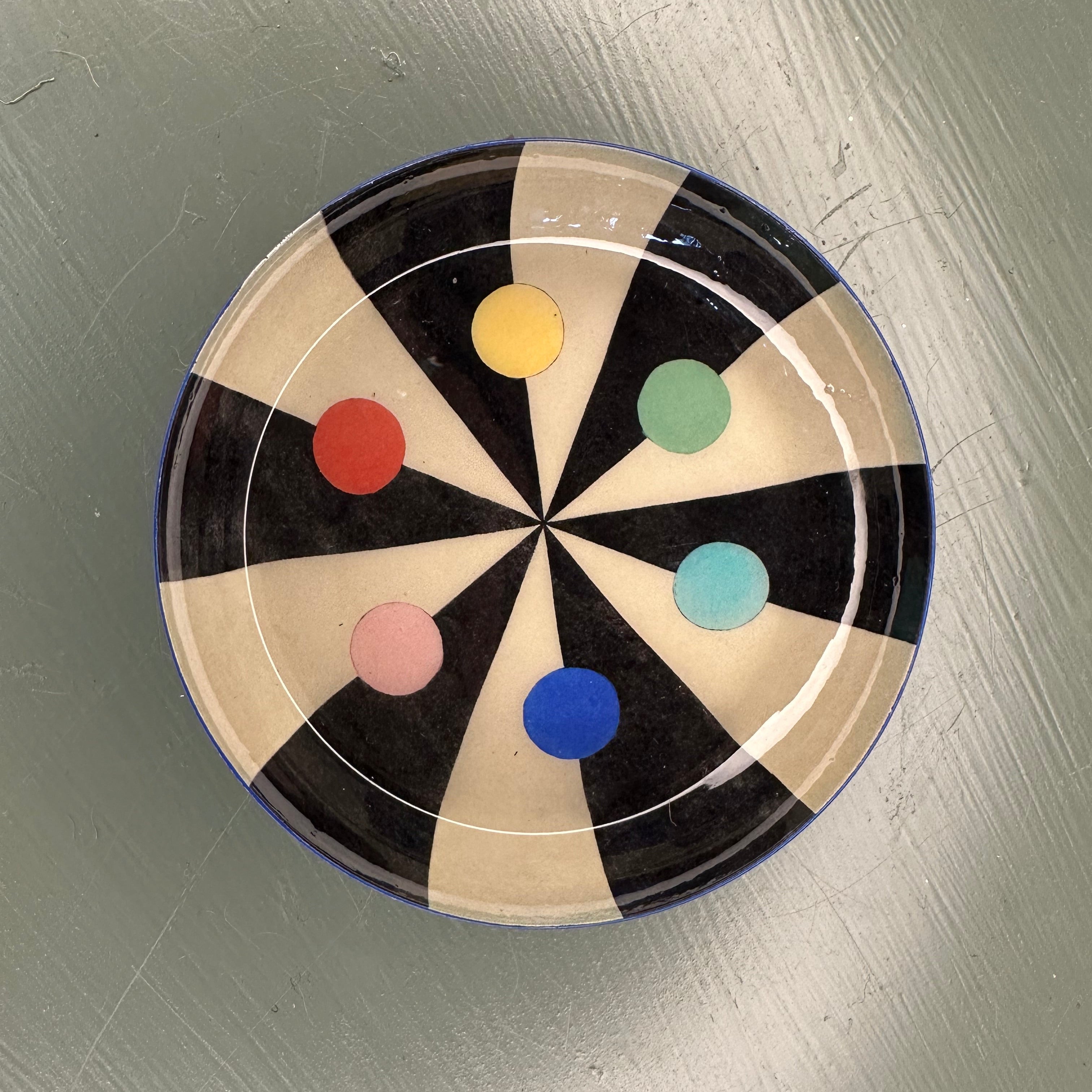 Decorative plate with colourful dots on a green surface