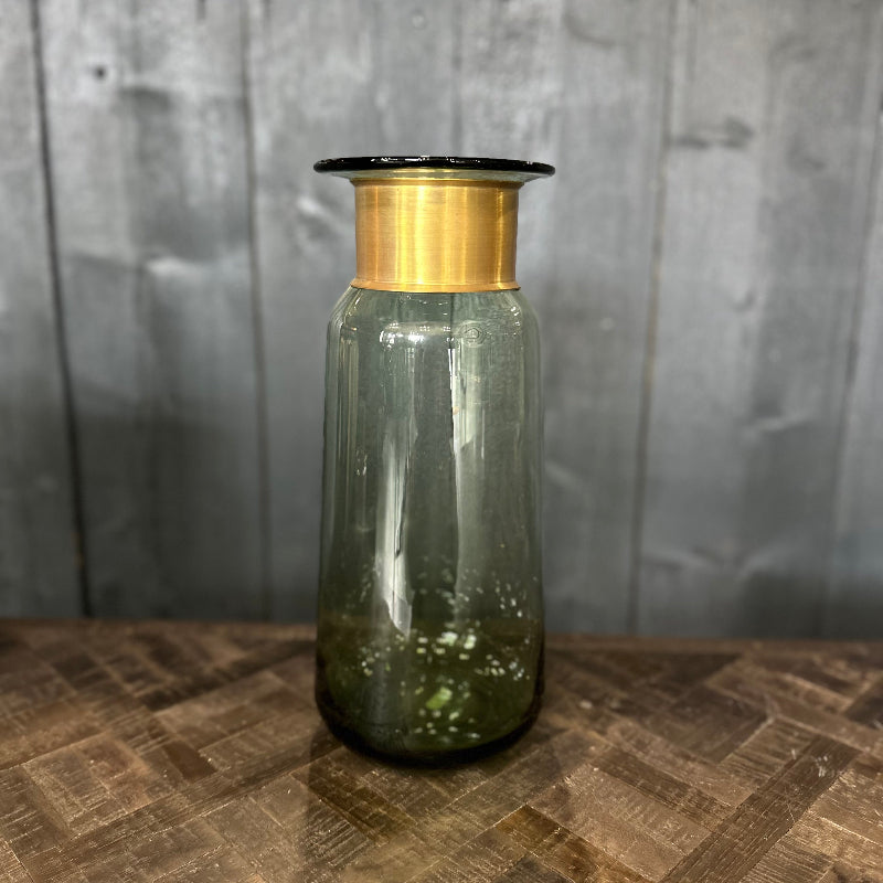 Green glass bottle with a gold cap on a wooden surface