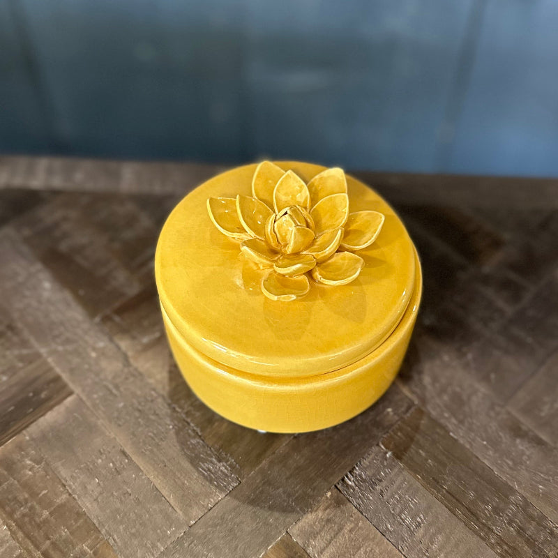 Yellow decorative box with a floral design on a wooden surface