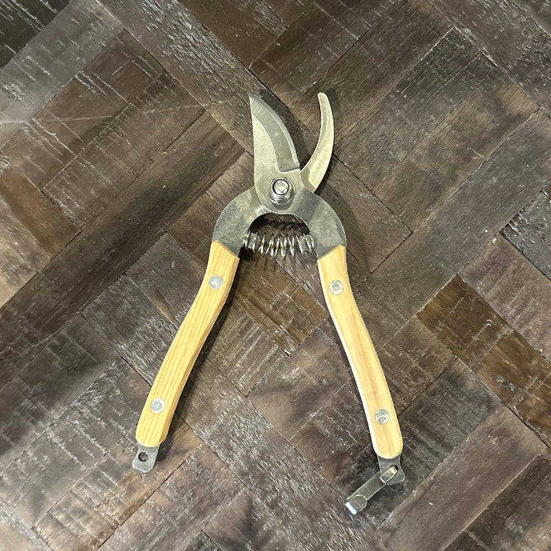 Pruning shears with wooden handles on a dark tiled floor