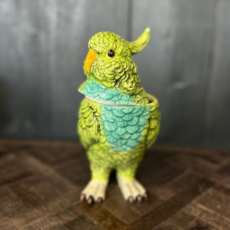 Green parrot-shaped teapot on a wooden surface with a dark background
