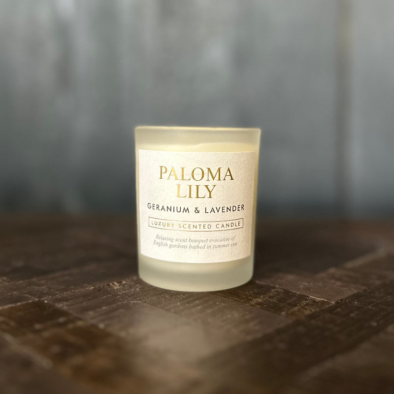 Paloma Lily scented candle on a wooden surface with a blurred background