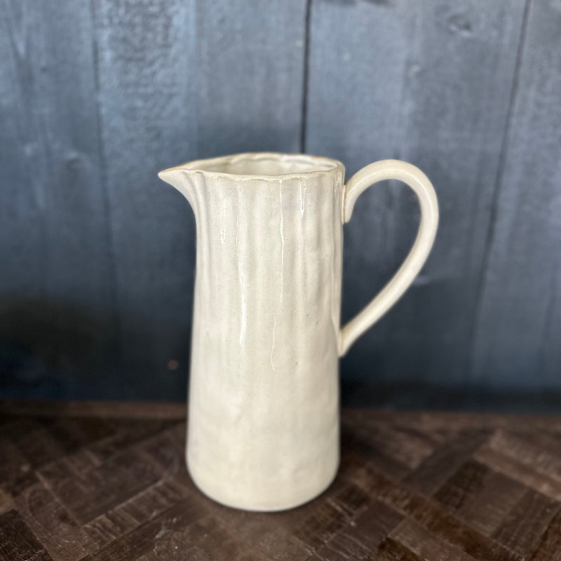 White ceramic pitcher on a dark wooden surface with a dark background
