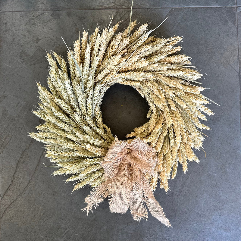Wheat wreath with a burlap bow on a dark surface
