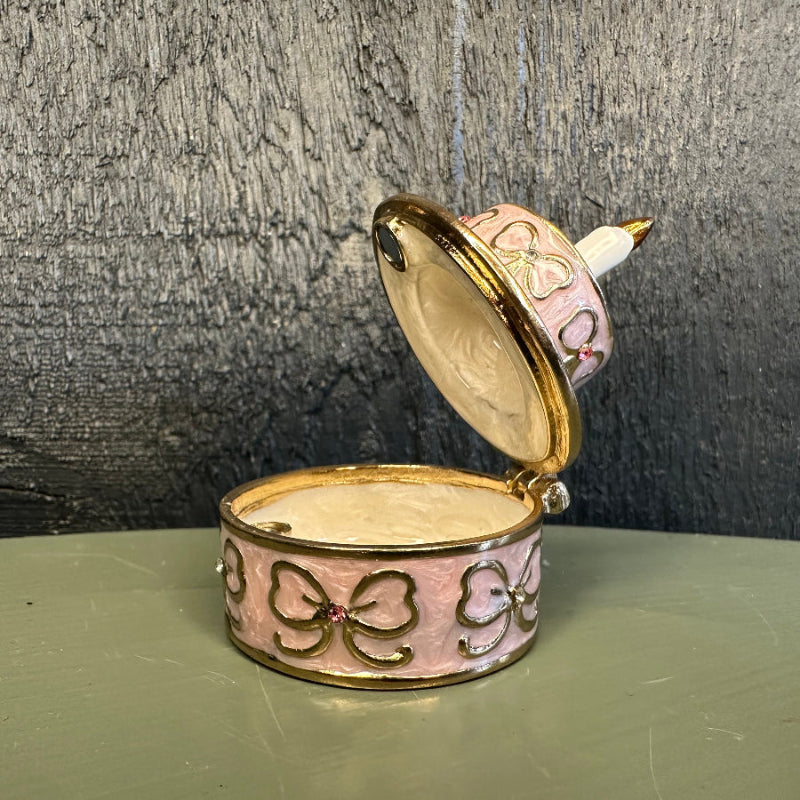 Decorative jewelry box with open lid on a textured surface