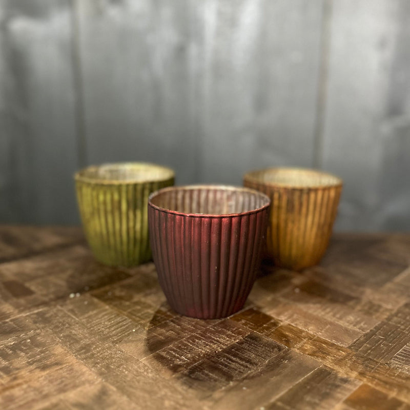 Three metallic cups on a wooden surface with a neutral background