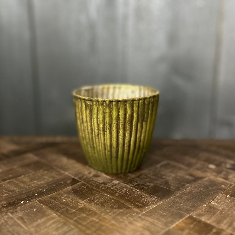 Green textured cup on a wooden surface with a blurred background
