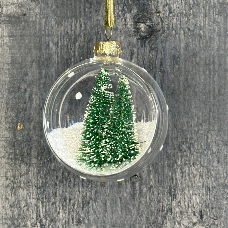 Christmas ornament with a clear ball containing a miniature Christmas tree on a wooden background