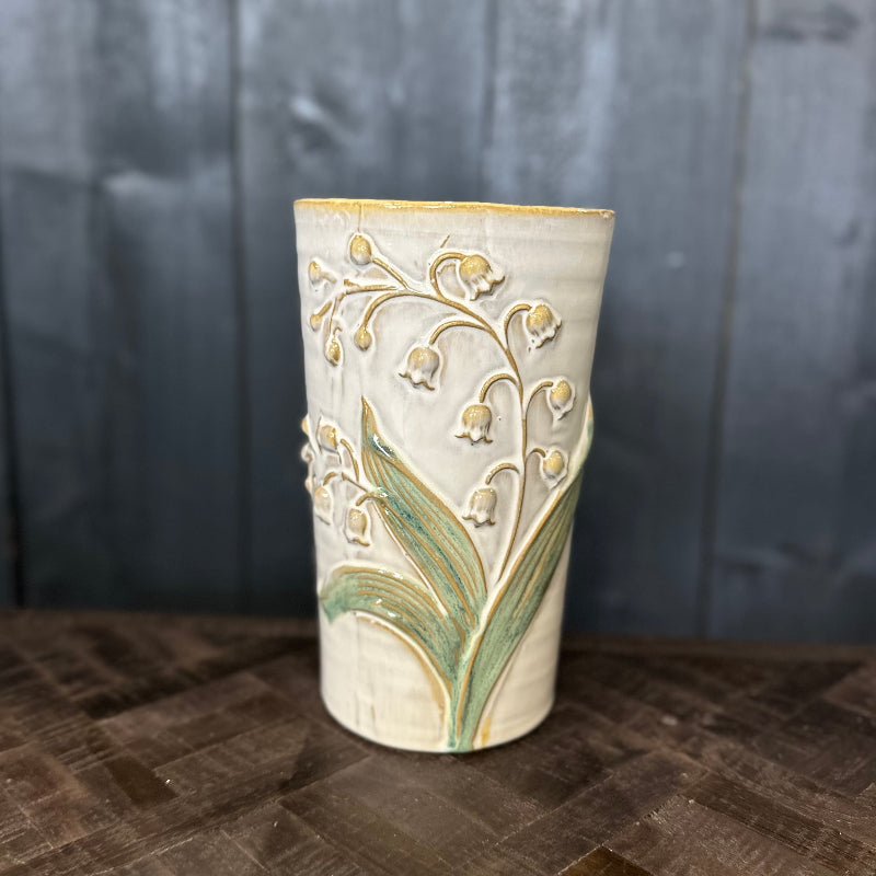 Ceramic vase with floral design on a wooden surface and dark wooden background