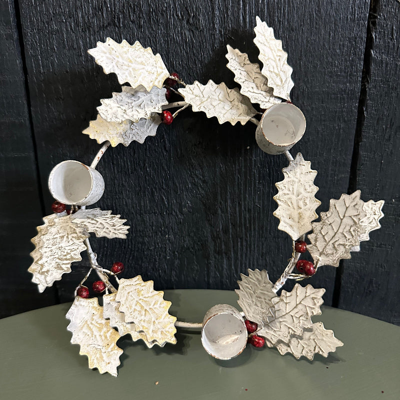 Decorative wreath with metallic leaves and red berries on a dark background