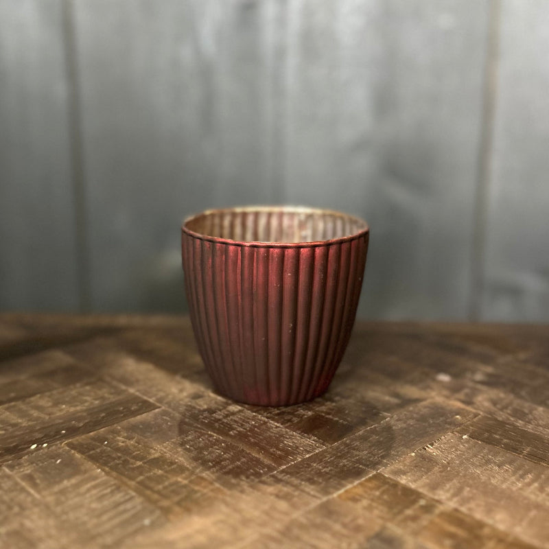 Bronze-colored cup with ribbed texture on a wooden surface