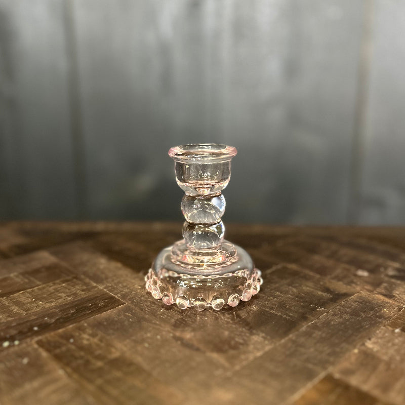 Clear glass candle holder on a wooden surface with a blurred background
