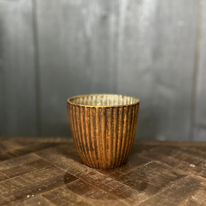 Bronze textured cup on a wooden surface with a gray background