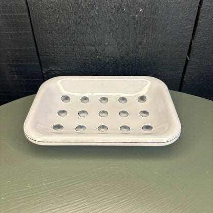 White soap dish with holes attached to a black surface
