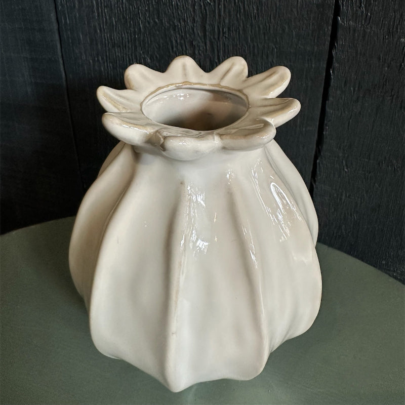 A white ceramic vase with a narrow neck, displayed against a dark background.