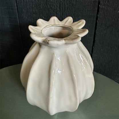 A white ceramic vase with a narrow neck, displayed against a dark background.