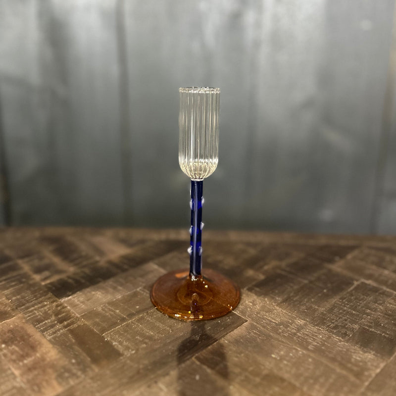 Clear glass with blue stem on a textured surface