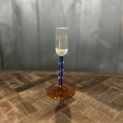 Clear glass with blue stem on a textured surface