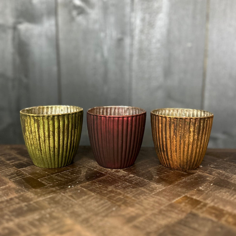 Three metallic cups of different colors on a textured surface with a neutral background