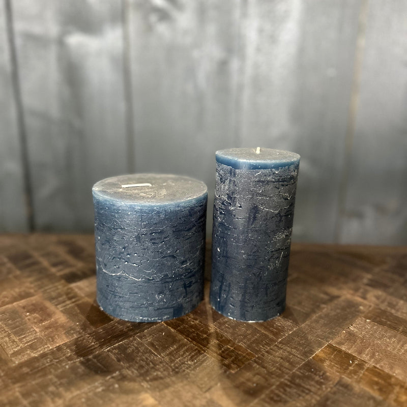 Two blue candles on a textured surface with a neutral background