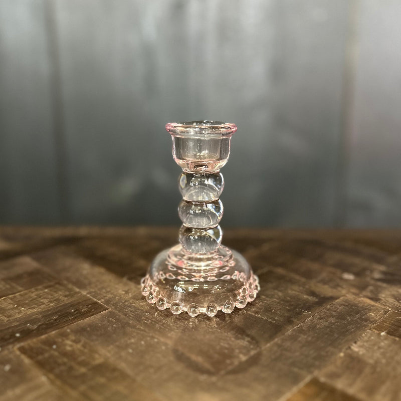 Clear glass candle holder on a textured surface with a blurred background