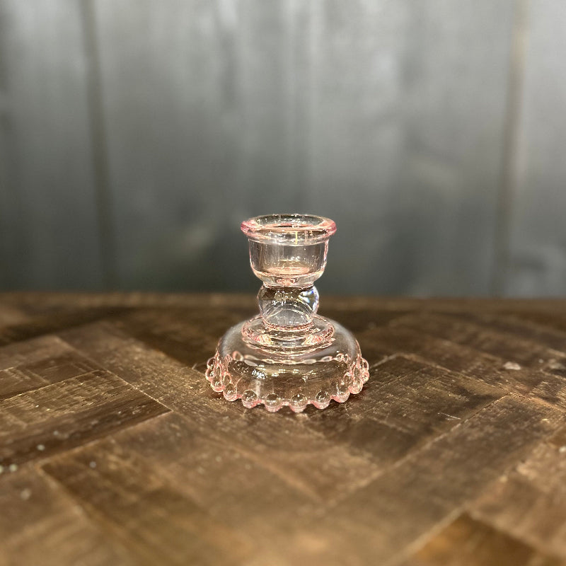 Clear glass candle holder on a wooden surface with a blurred background