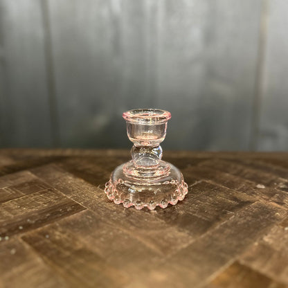 Clear glass candle holder on a wooden surface with a blurred background