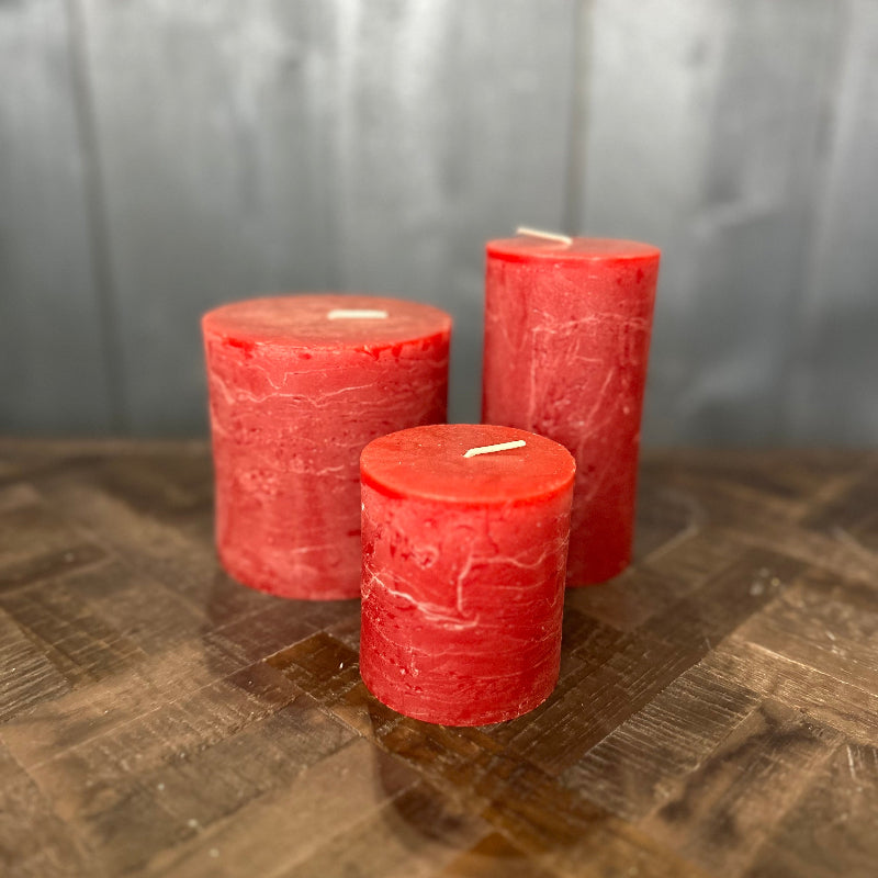 Three red candles on a wooden surface with a gray background