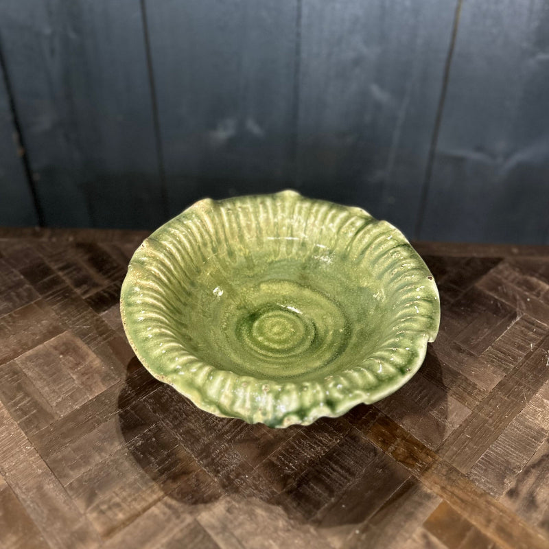 Green ceramic bowl on a textured surface with a dark wooden background